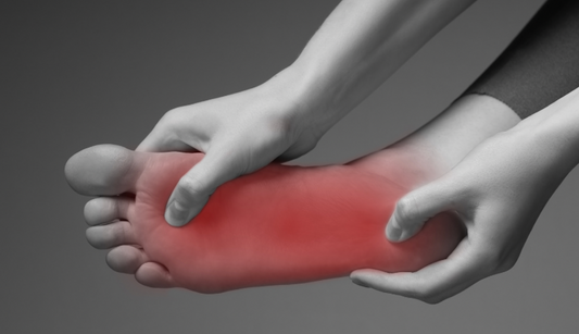 Neuropátiás lábfájdalom: Egy kéz masszírozza a pirossal kiemelt, fájdalmas területet egy láb talpán, amely bizsergésre vagy égő érzésre utalhat.